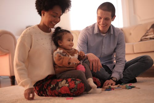 Photo of Man and Woman Having Fun With Their Child