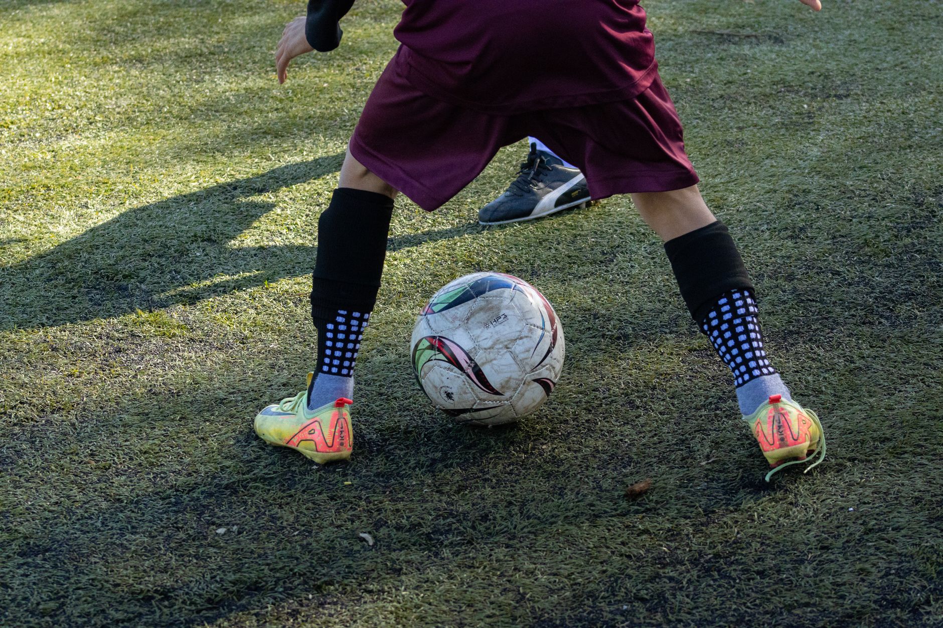 teenage footballer controlling a ball on a quiet grass pitch during early morning training