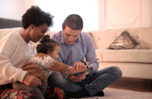 Foto Van Familie Zittend Op De Vloer Tijdens Het Lezen Van Boek