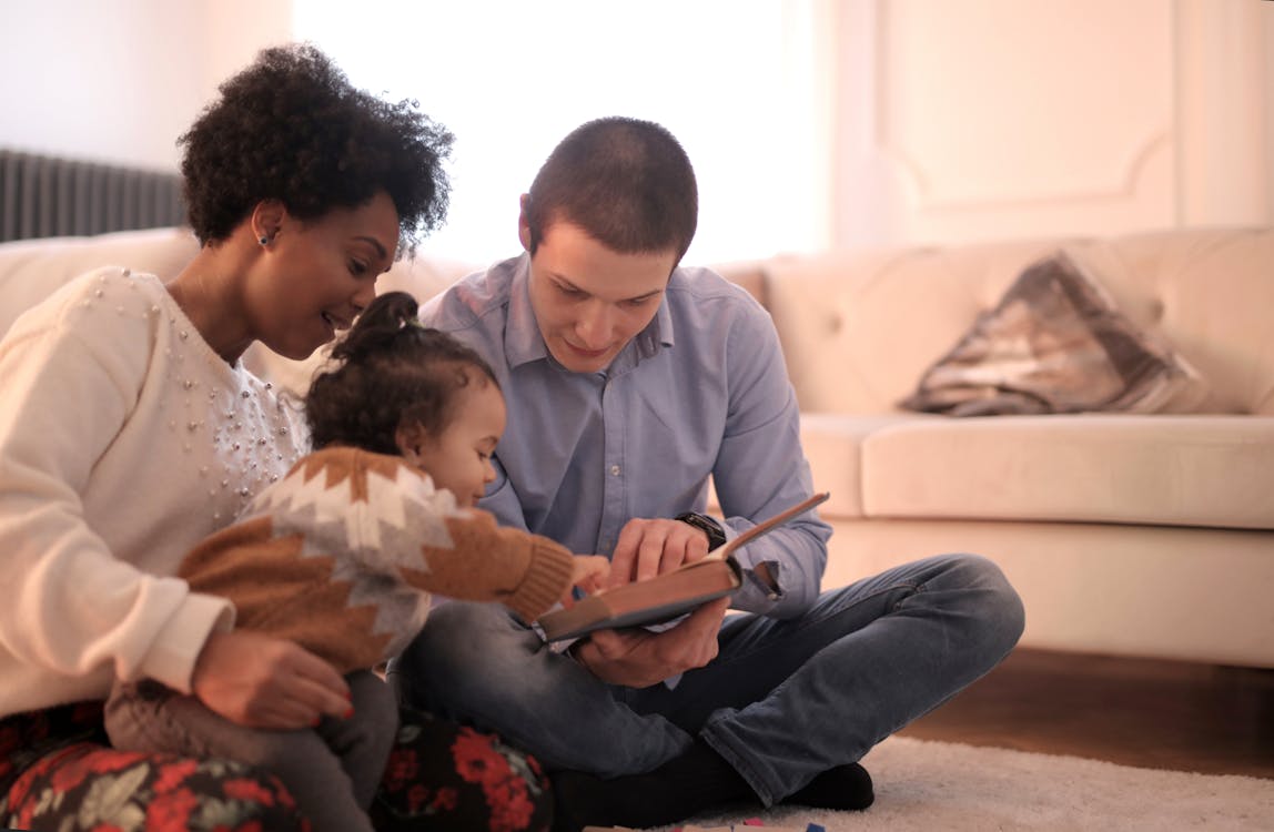 Free Photo of Family Sitting on Floor While Reading Book Stock Photo