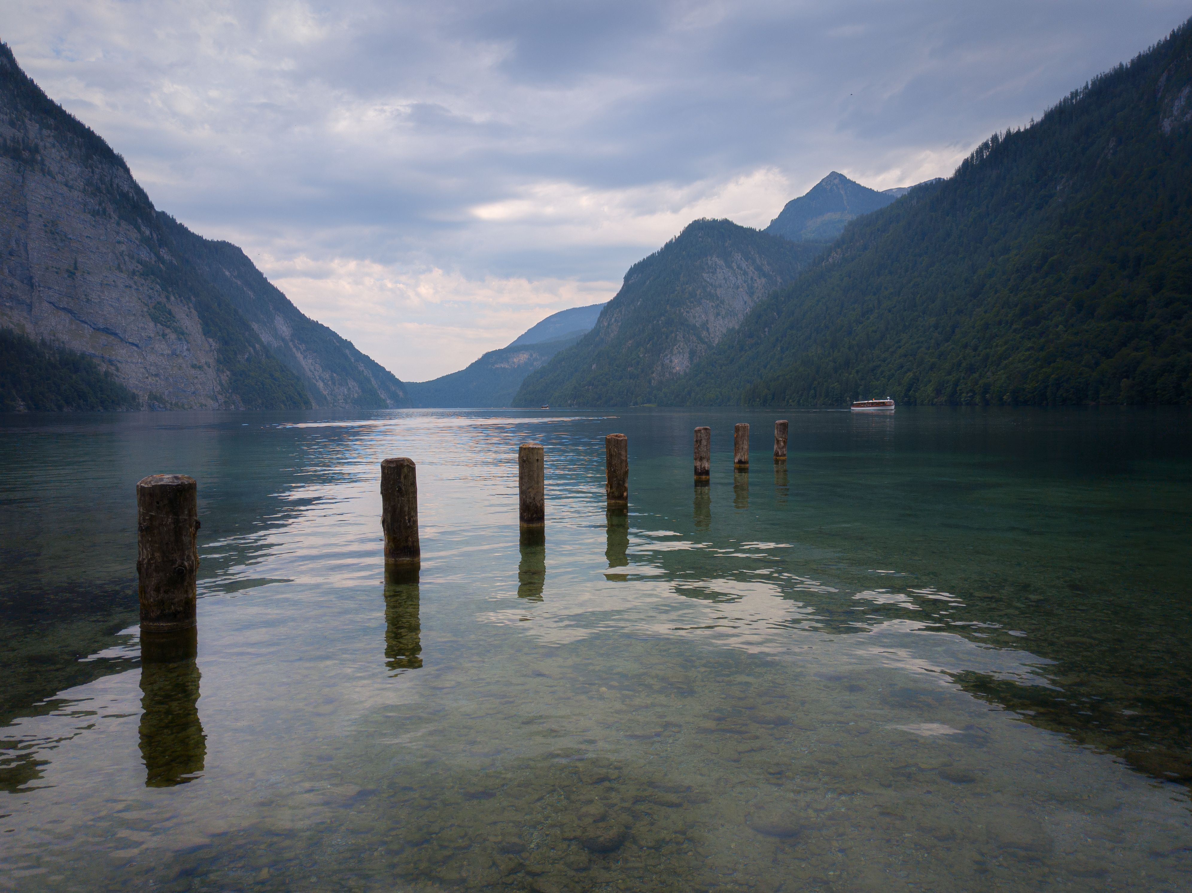 Peaceful scene of a serene lake surrounded by mountains under a cloudy sky.