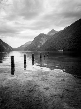 Peaceful black and white landscape of a calm lake surrounded by mountains, evoking tranquility.