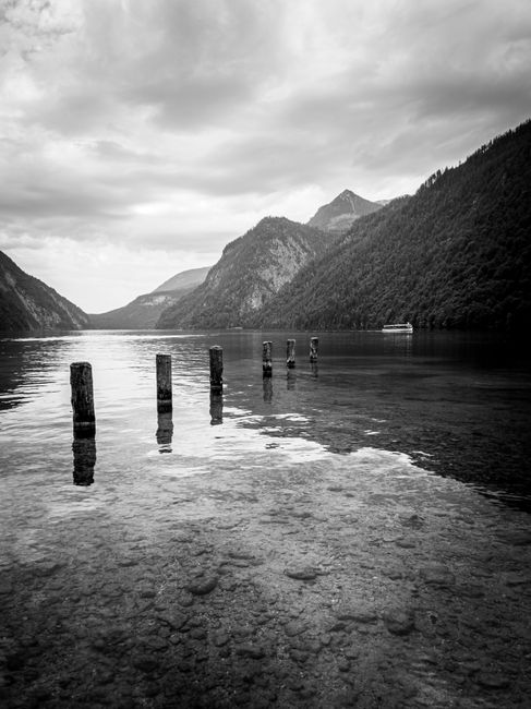 Peaceful black and white landscape of a calm lake surrounded by mountains, evoking tranquility.