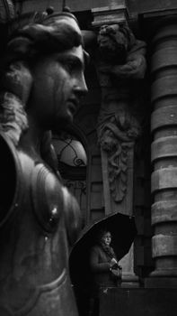 Black and white street scene featuring a statue and person with umbrella in São Paulo.