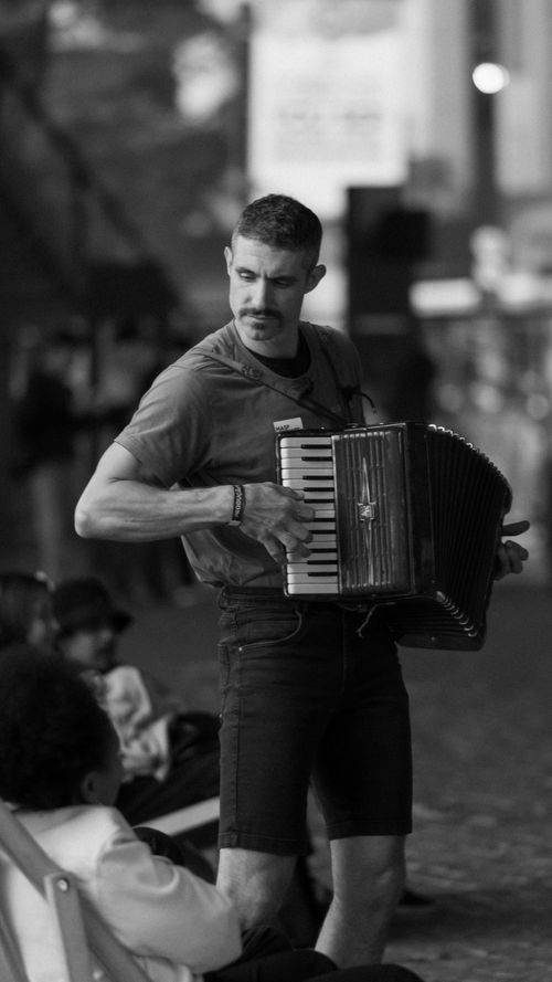 Free A man energetically plays an accordion during a lively outdoor street performance. Stock Photo