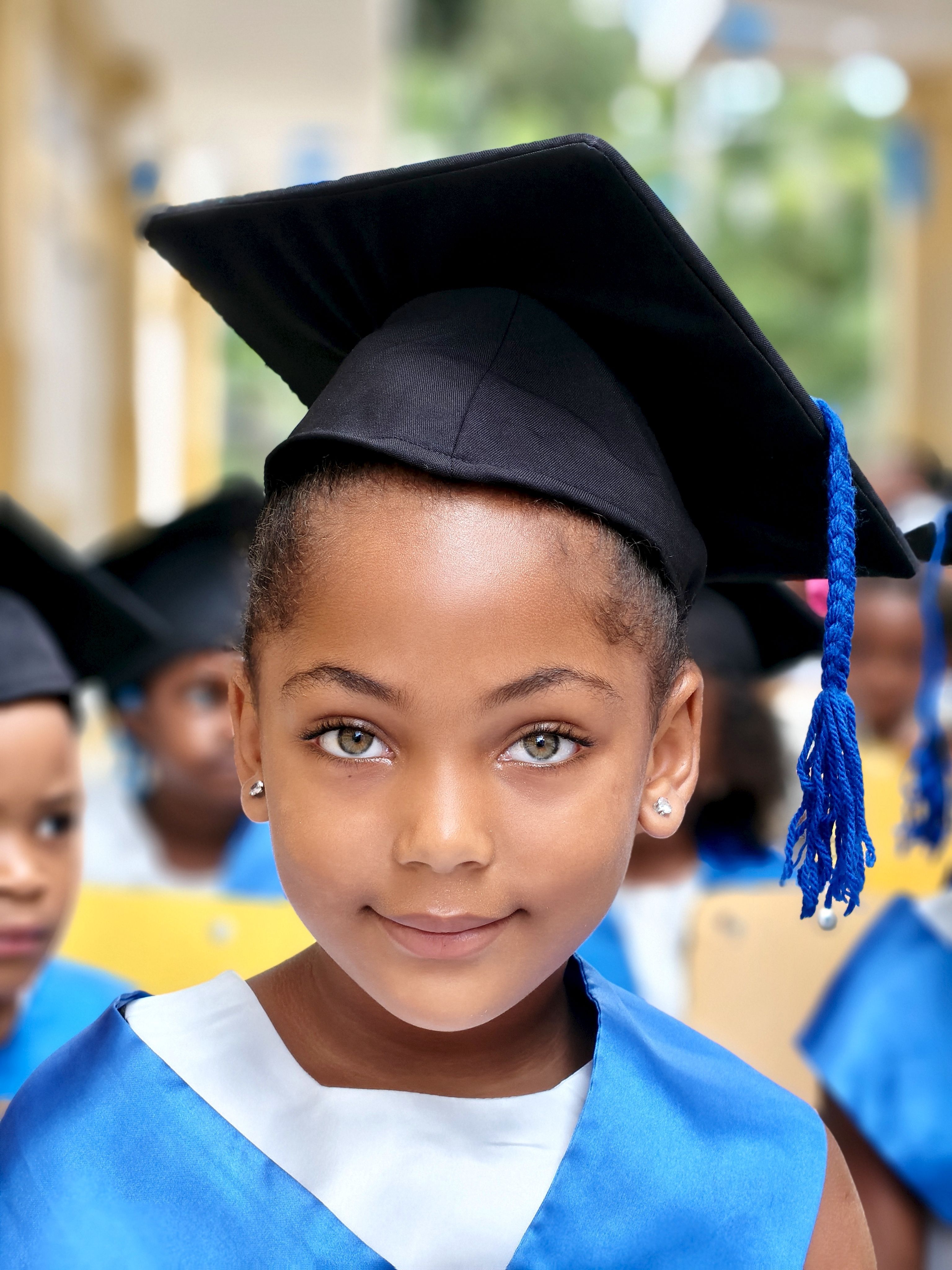 A young girl in graduation attire during a ceremony, symbolizing achievement and future potential.