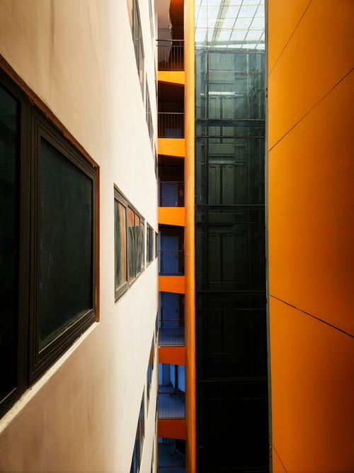 Free An artistic view of an indoor modern architectural space with striking orange accents and geometric symmetry. Stock Photo
