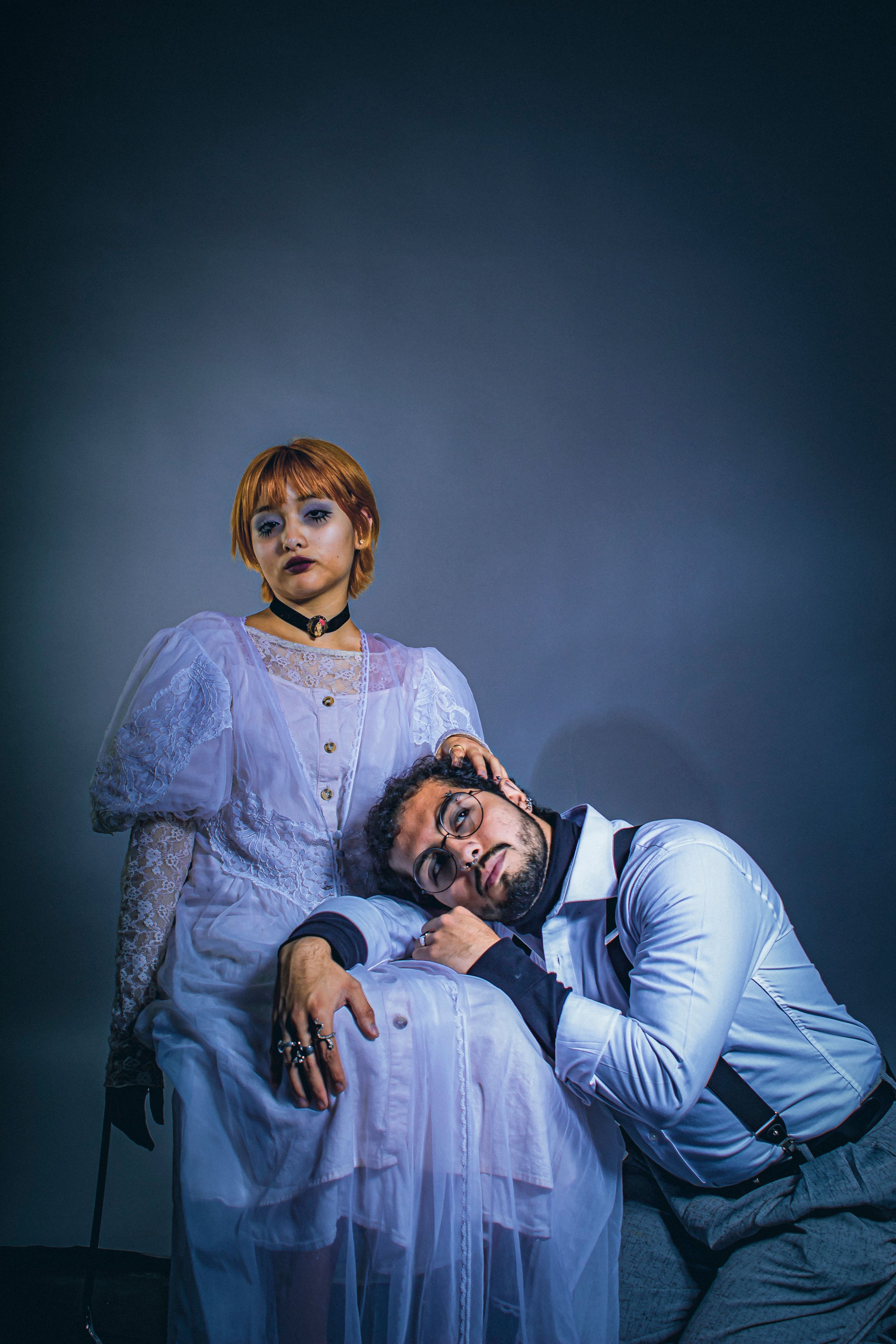 A vintage-style portrait featuring two adults in artistic Victorian-inspired attire.