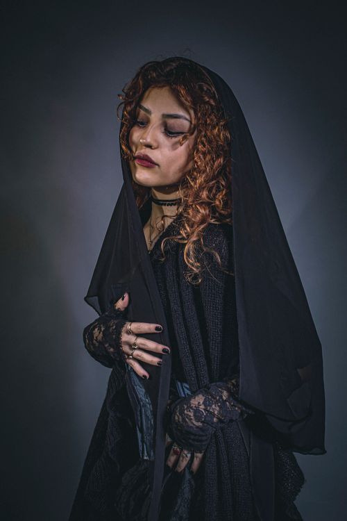 Free Mysterious red-haired woman in dark Gothic Victorian attire evokes dramatic and moody atmosphere. Stock Photo