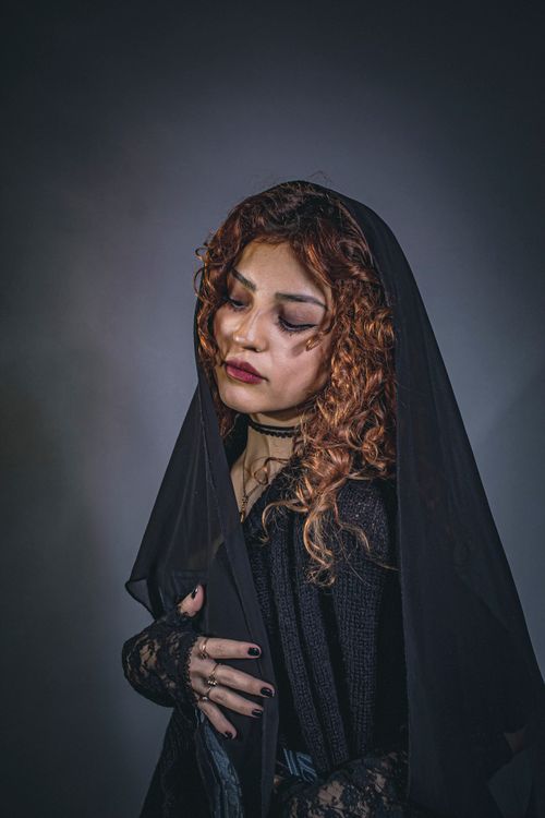 Free A woman with curly hair and a black veil in a dramatic, somber mood. Stock Photo