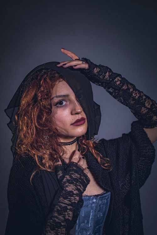Free Dramatic portrait of a woman in Victorian-inspired attire with lace gloves. Stock Photo