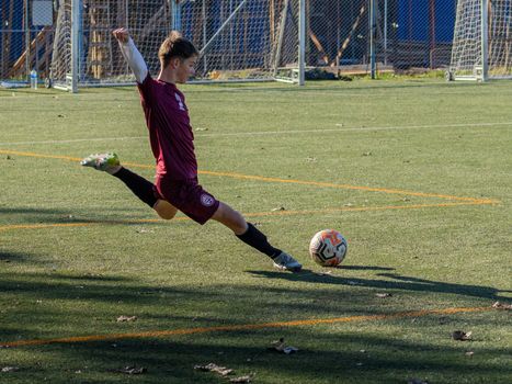 A young soccer player in action, kicking a ball during a game on an outdoor field.