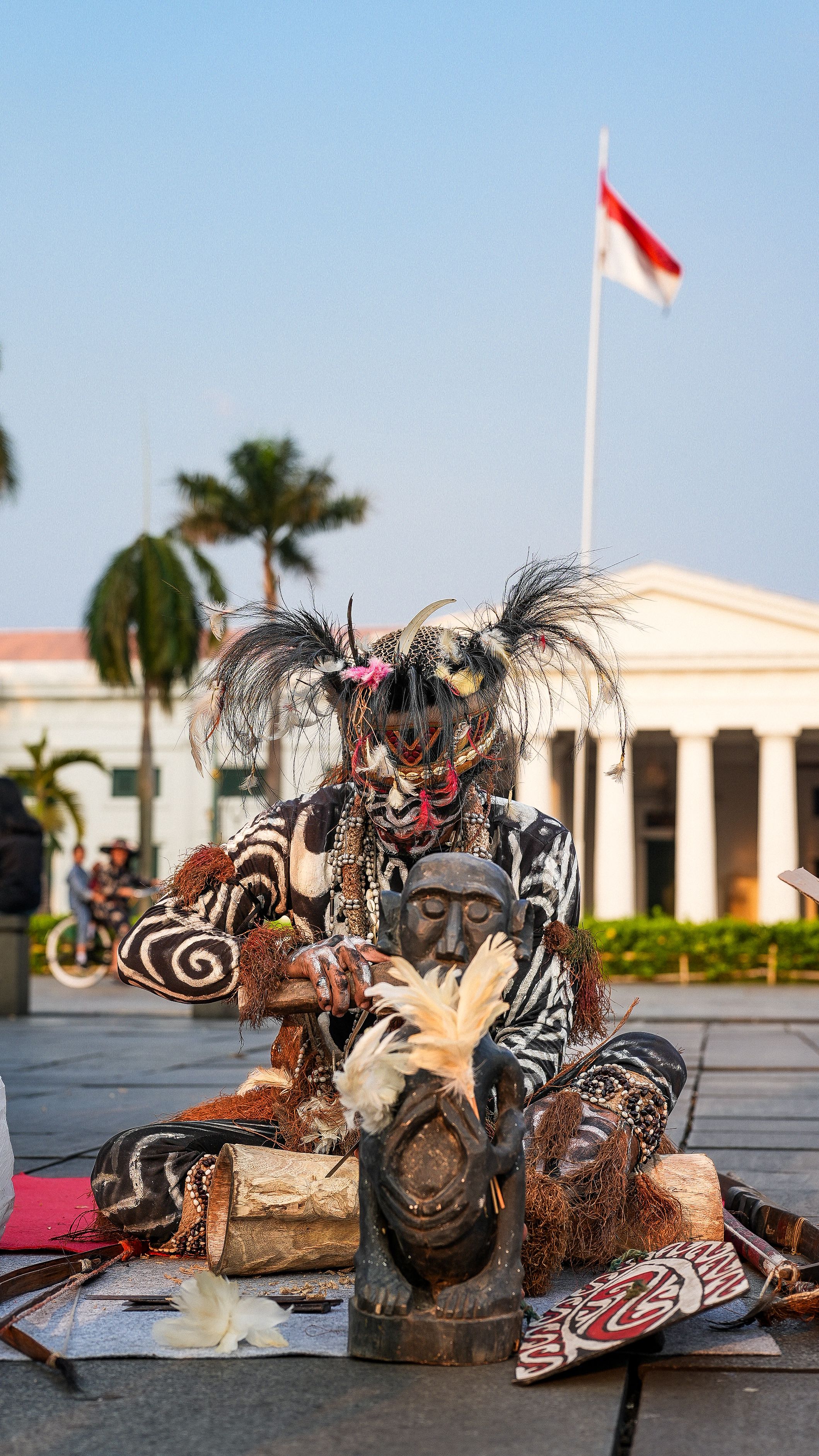 Street performer in traditional costume performing at Jakarta's iconic location.