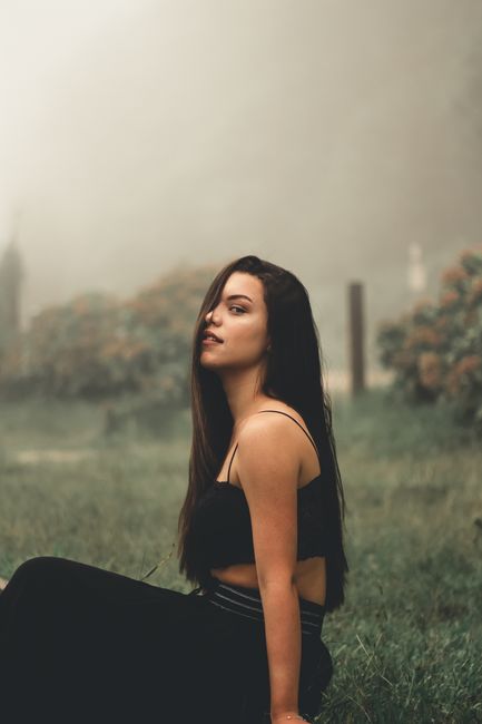 A woman sitting in a misty garden, exuding confidence and serenity.