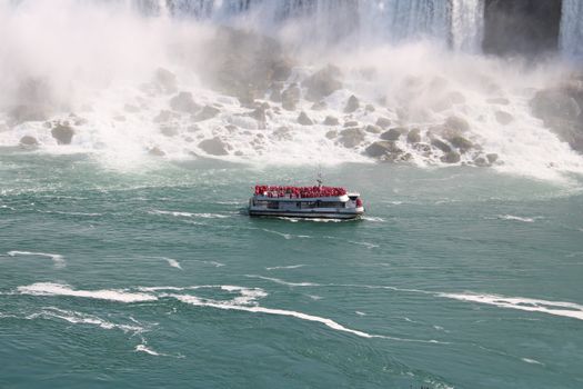 A tour boat navigates the misty waters of Niagara Falls, offering a thrilling close-up view.