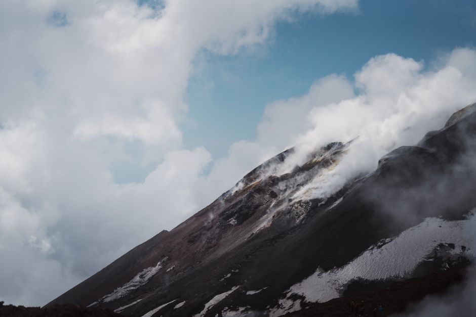 Stunning capture of Mount Etna releasing steam and smoke under a cloudy sky.