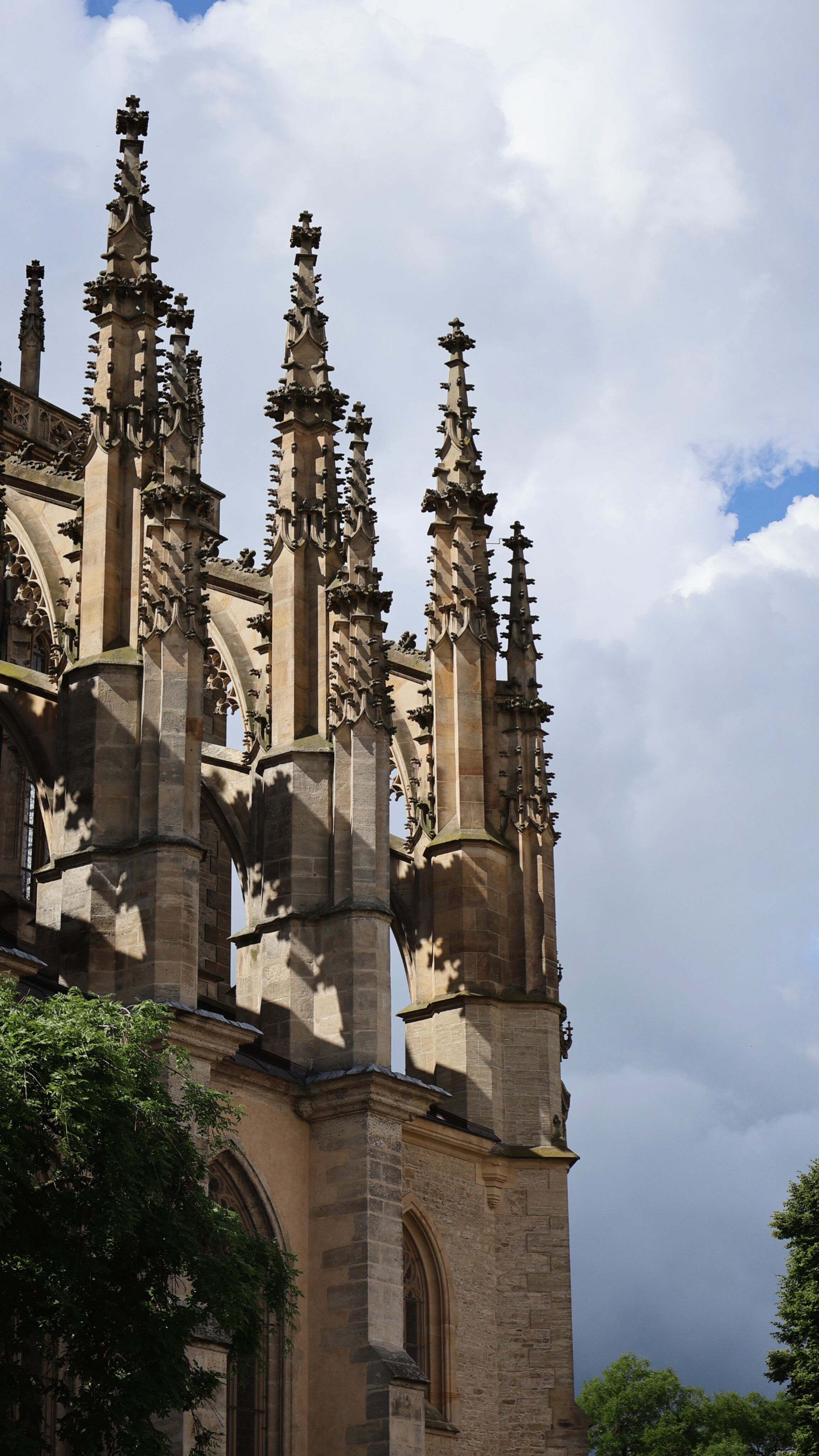 Detailed view of Gothic spires of a church in Kutná Hora, Czechia, under a dramatic sky.