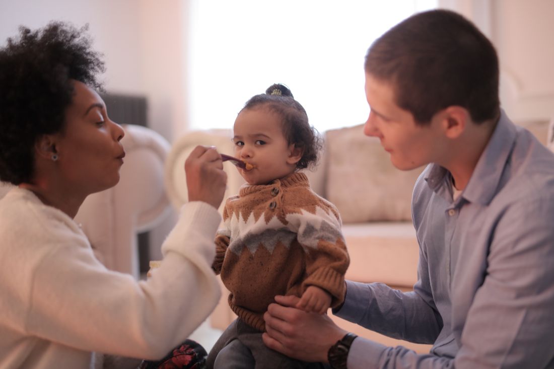 Parents spoon-feeding their baby a meal