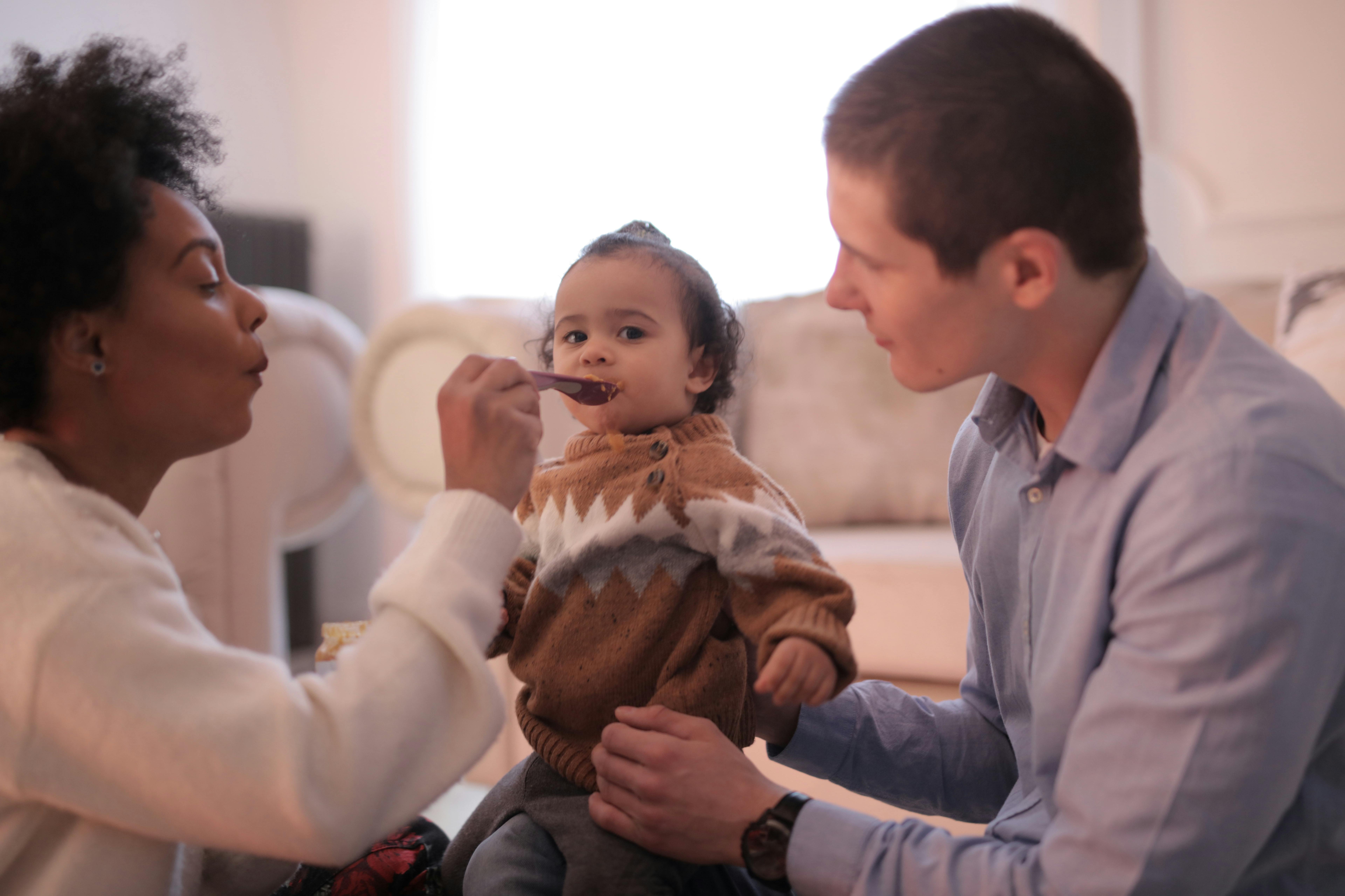 A nurturing indoor scene of parents feeding their baby, capturing love and togetherness.