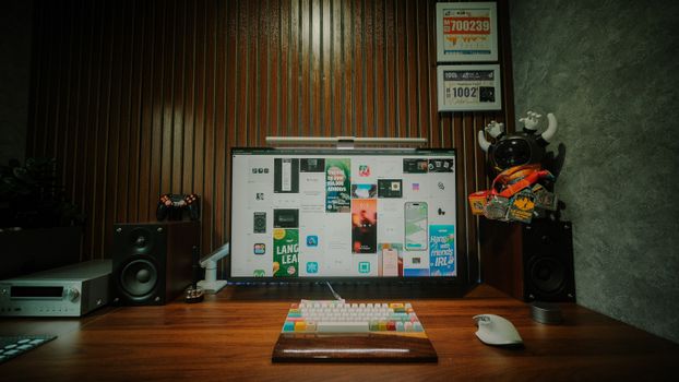 Stylish desk setup with monitor, speakers, keyboard, and a decorative figure.