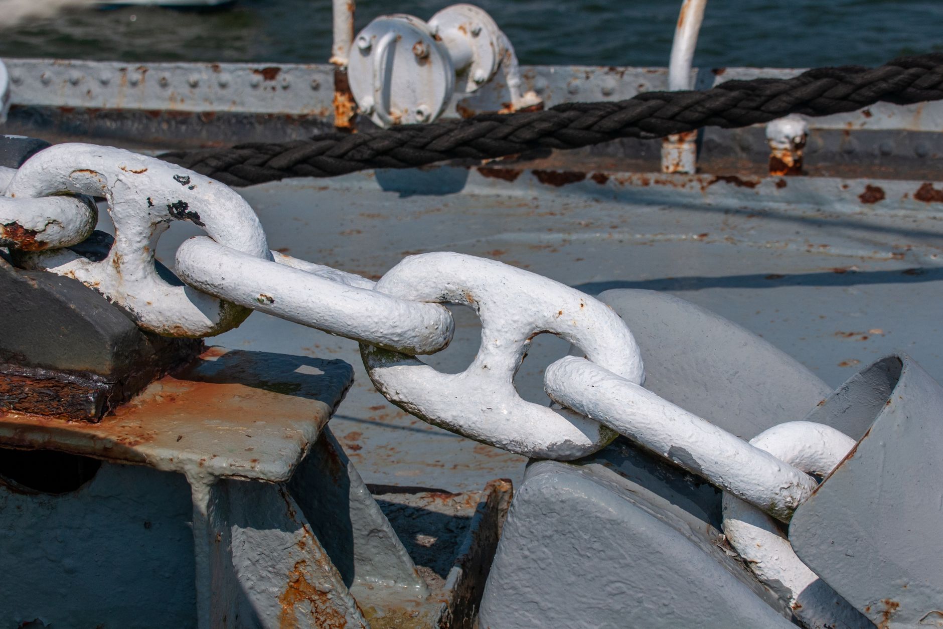 Detailed view of a weathered anchor chain on a docked ship, showing rustic textures and maritime usage.