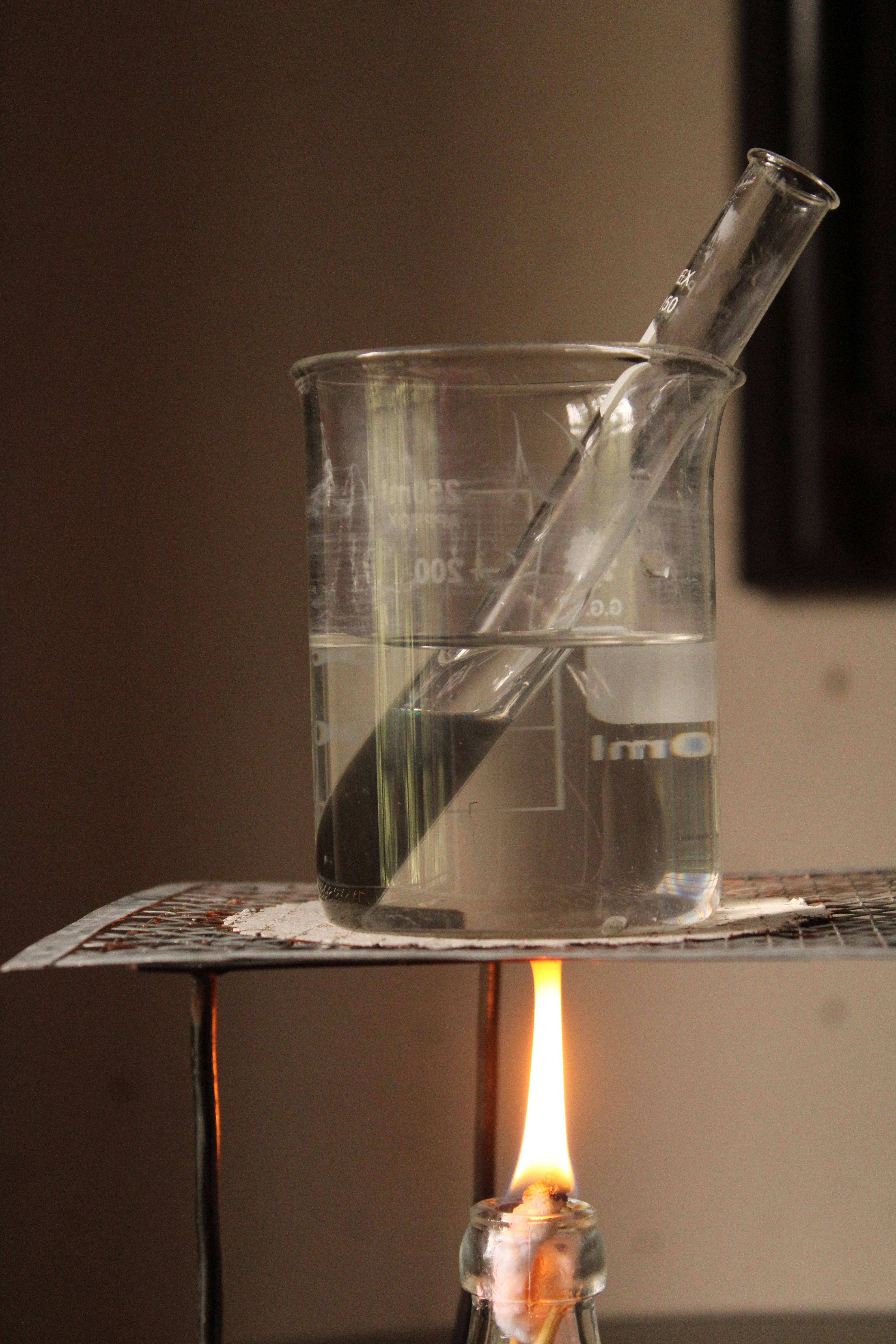 Close-up of a beaker over open flame in a lab setting.