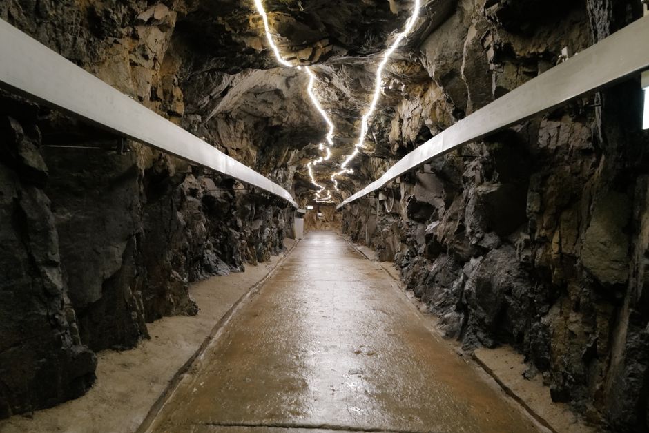 A well-lit underground tunnel with rugged rock walls and modern lighting.