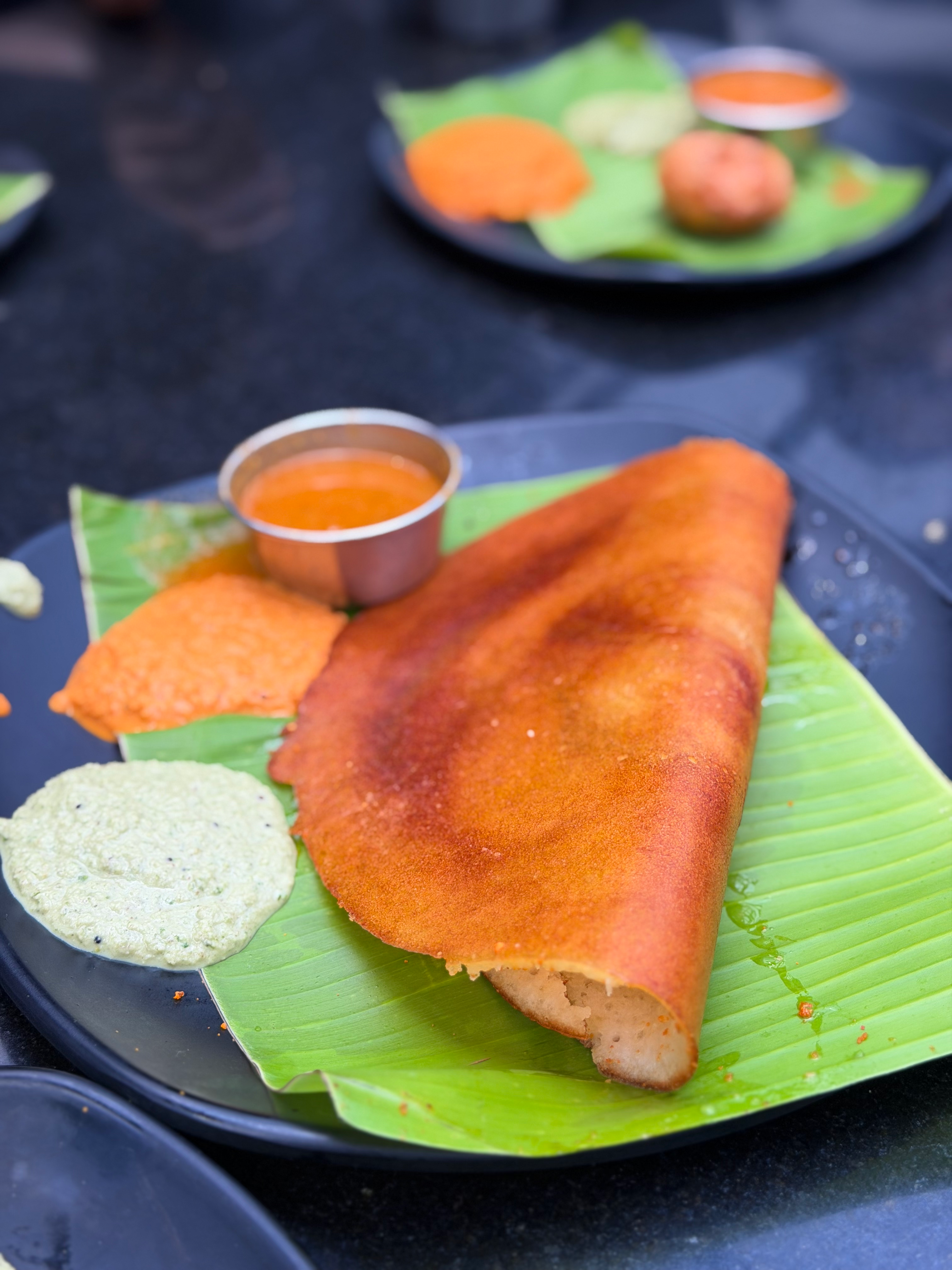 Delicious masala dosa served with spicy chutneys on a banana leaf in Bengaluru, India.