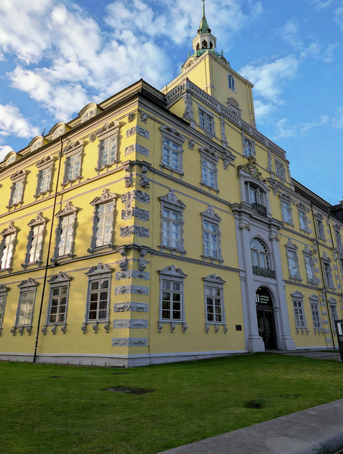 Free Historic yellow baroque building with intricate details and a tower under a clear blue sky. Stock Photo
