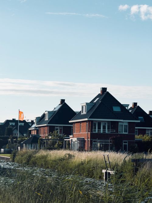 Free Traditional Dutch canal houses with pitched roofs and brick facades under clear skies. Stock Photo