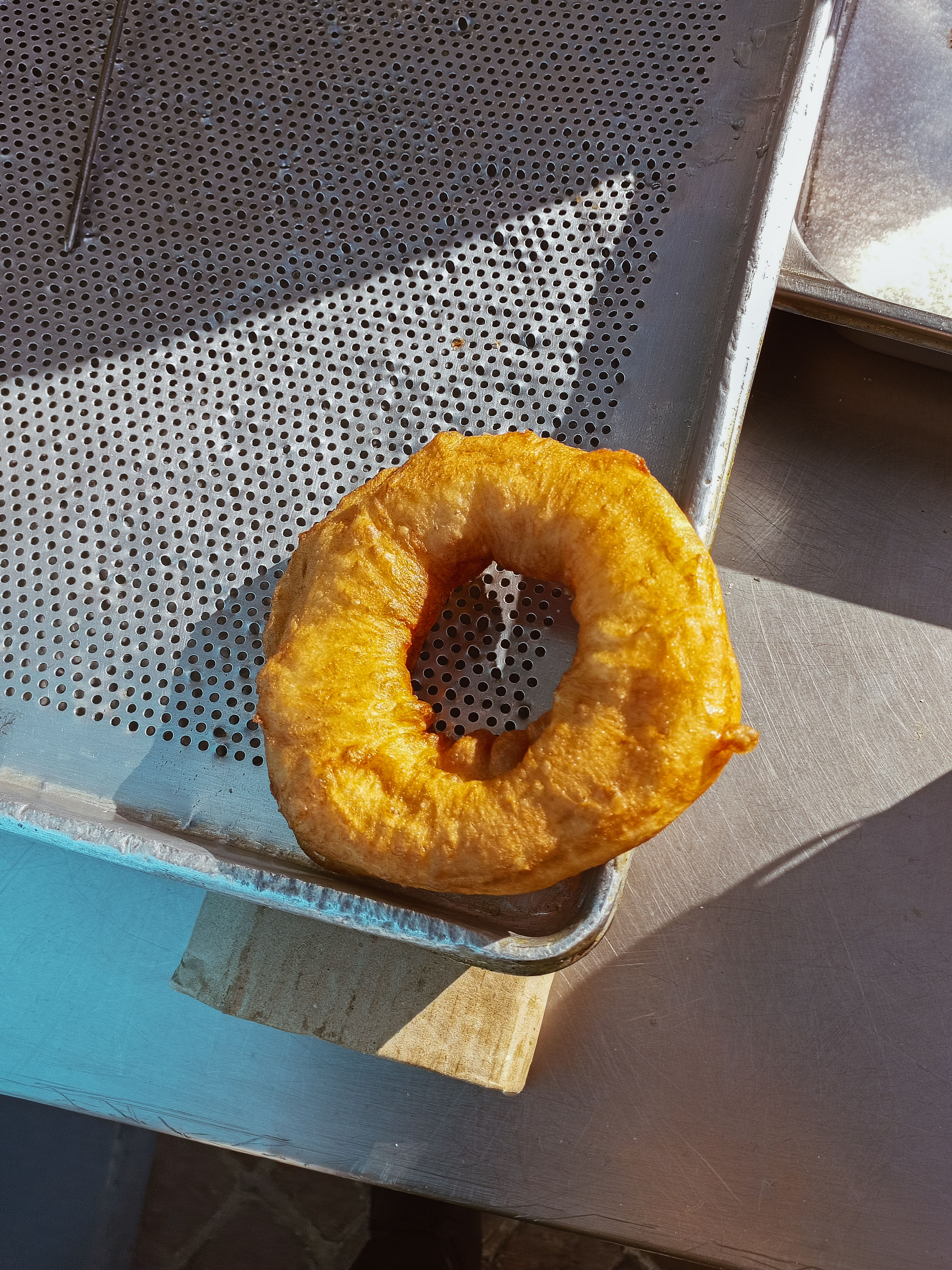 A freshly fried Tunisian doughnut resting on a baking tray, perfect for food enthusiasts.