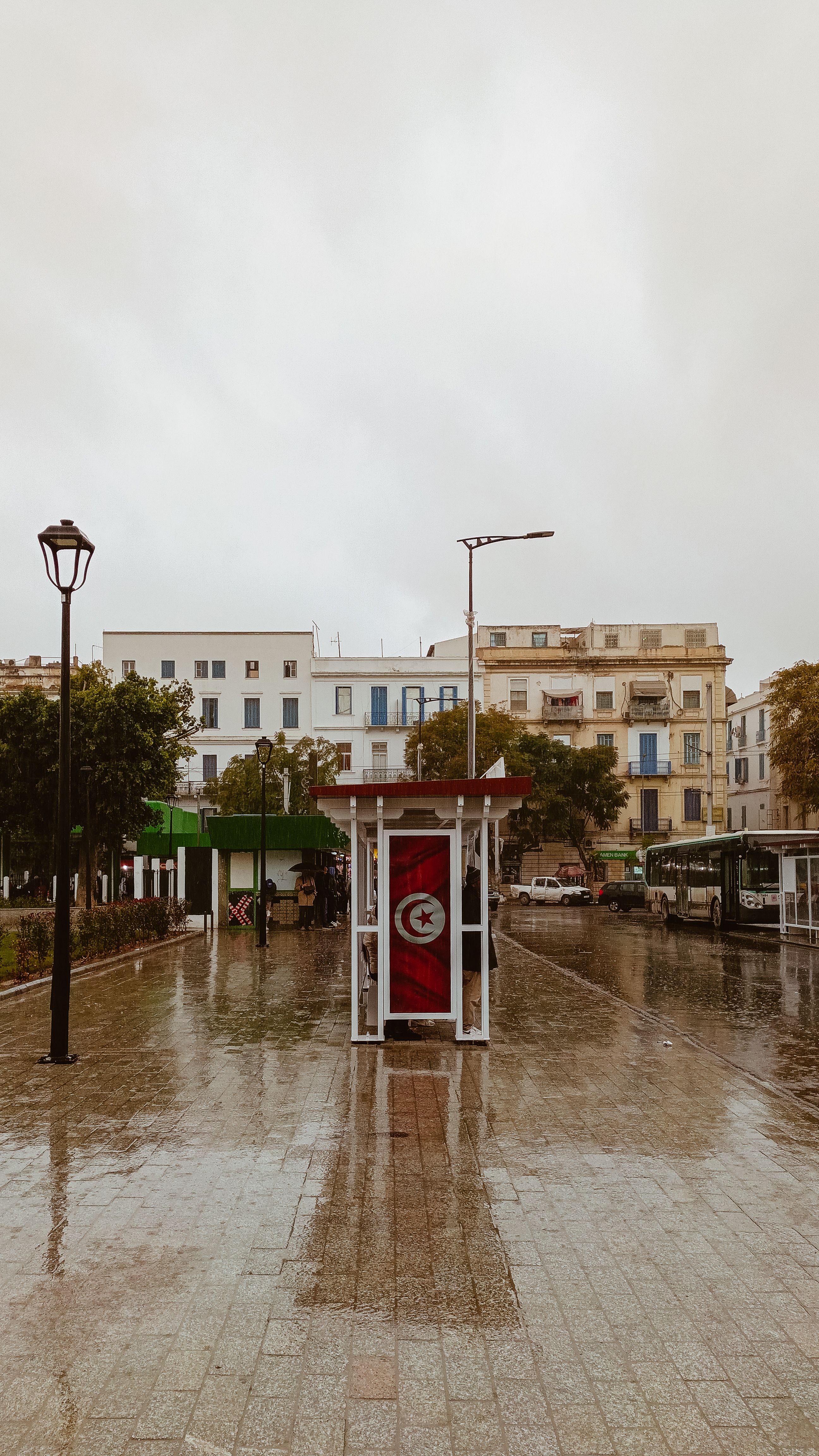 Rain-soaked city center in Tunis featuring the Tunisian flag.