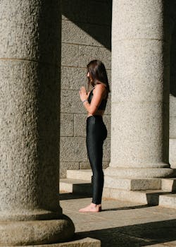 一名女子在沐浴着阳光的石柱间摆出瑜伽姿势