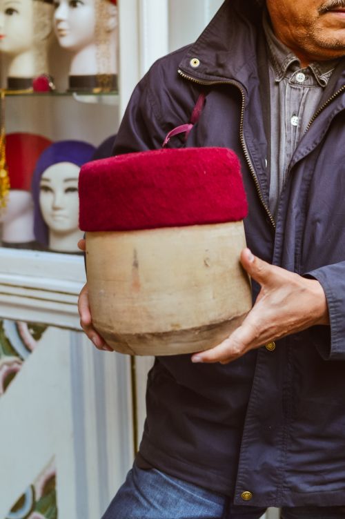 Free A man displays a red fez hat outside a hat shop in Tunis, Tunisia. Stock Photo