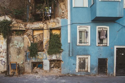 Free An old building facade showcasing urban decay alongside vivid blue walls, merging old and new textures. Stock Photo