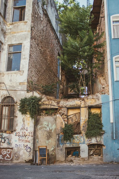 Free A decaying urban building overgrown with greenery, featuring graffiti and rustic architecture. Stock Photo