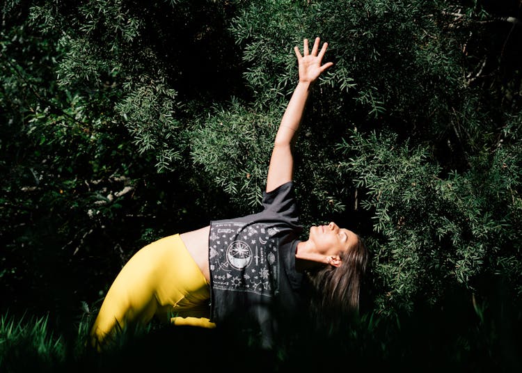 Photo Of Woman Doing Yoga Near Dark Green Leaves