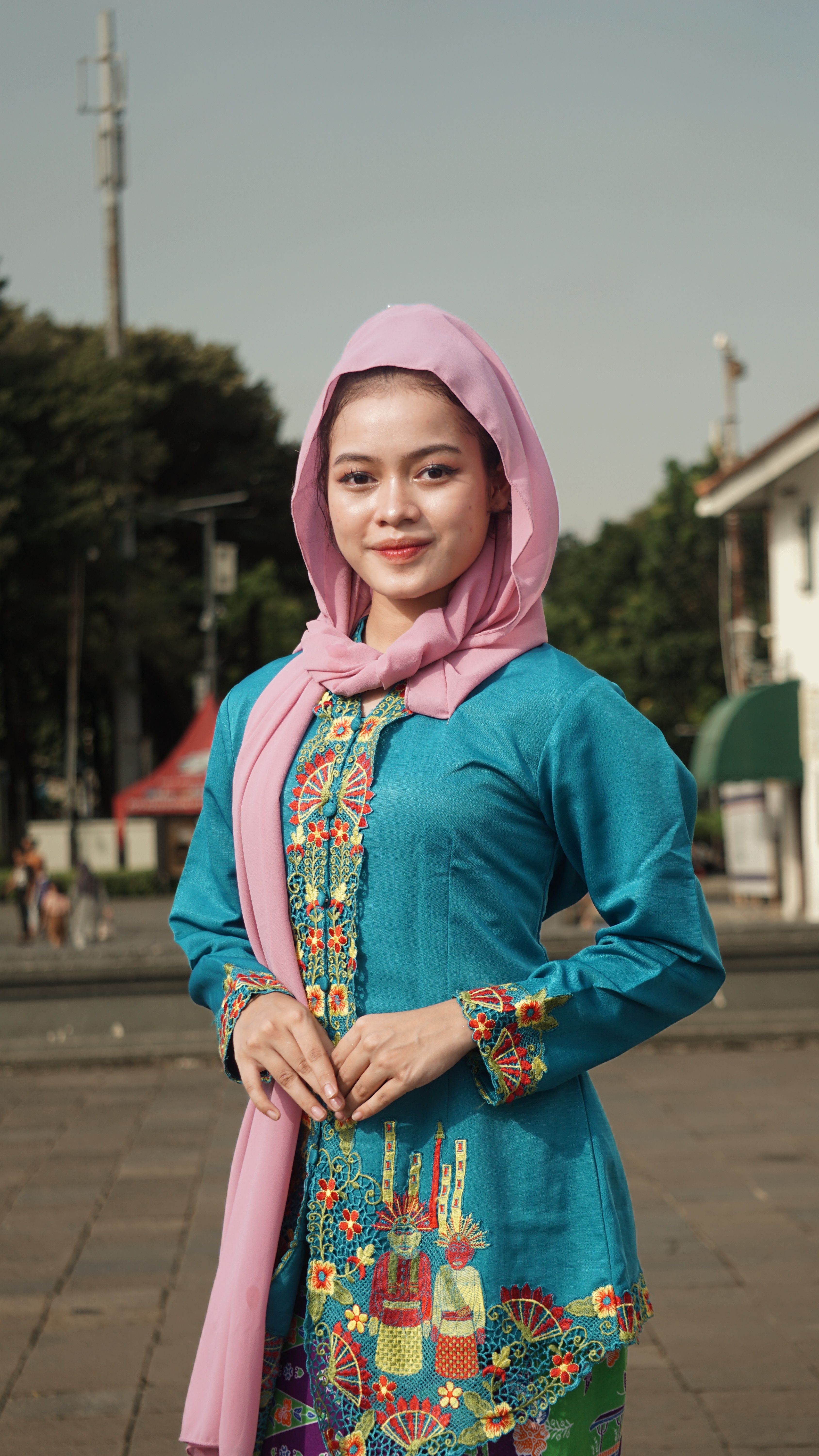 Portrait of a young woman in colorful traditional attire outdoors in Jakarta.