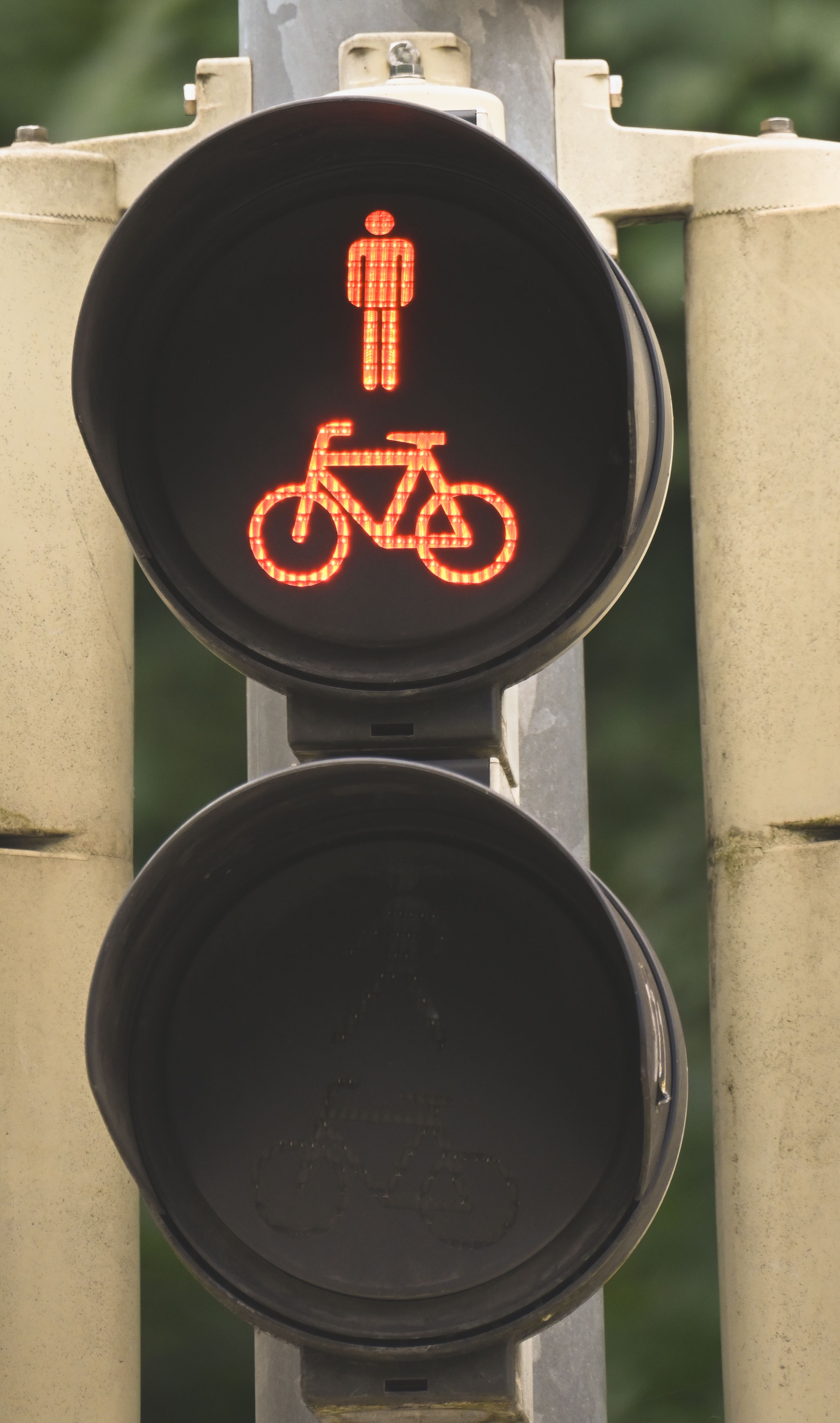 Traffic signal with red light for bicycles and pedestrians, signifying stop.