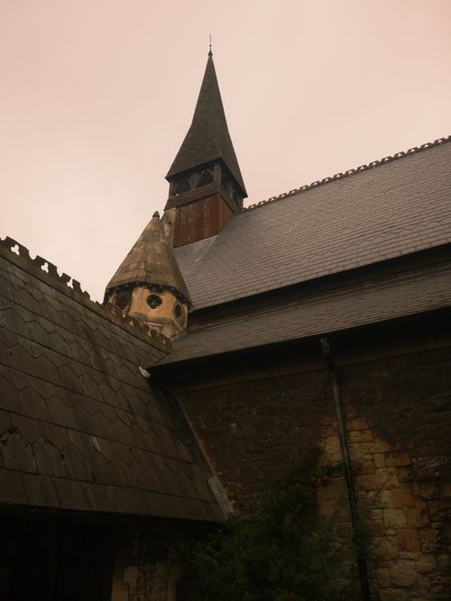 Free A historic stone church featuring a tall steeple and unique architecture against a muted sky. Stock Photo