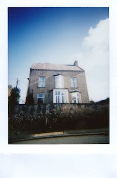 A charming vintage-style brick house captured with a Polaroid effect under a bright blue sky.