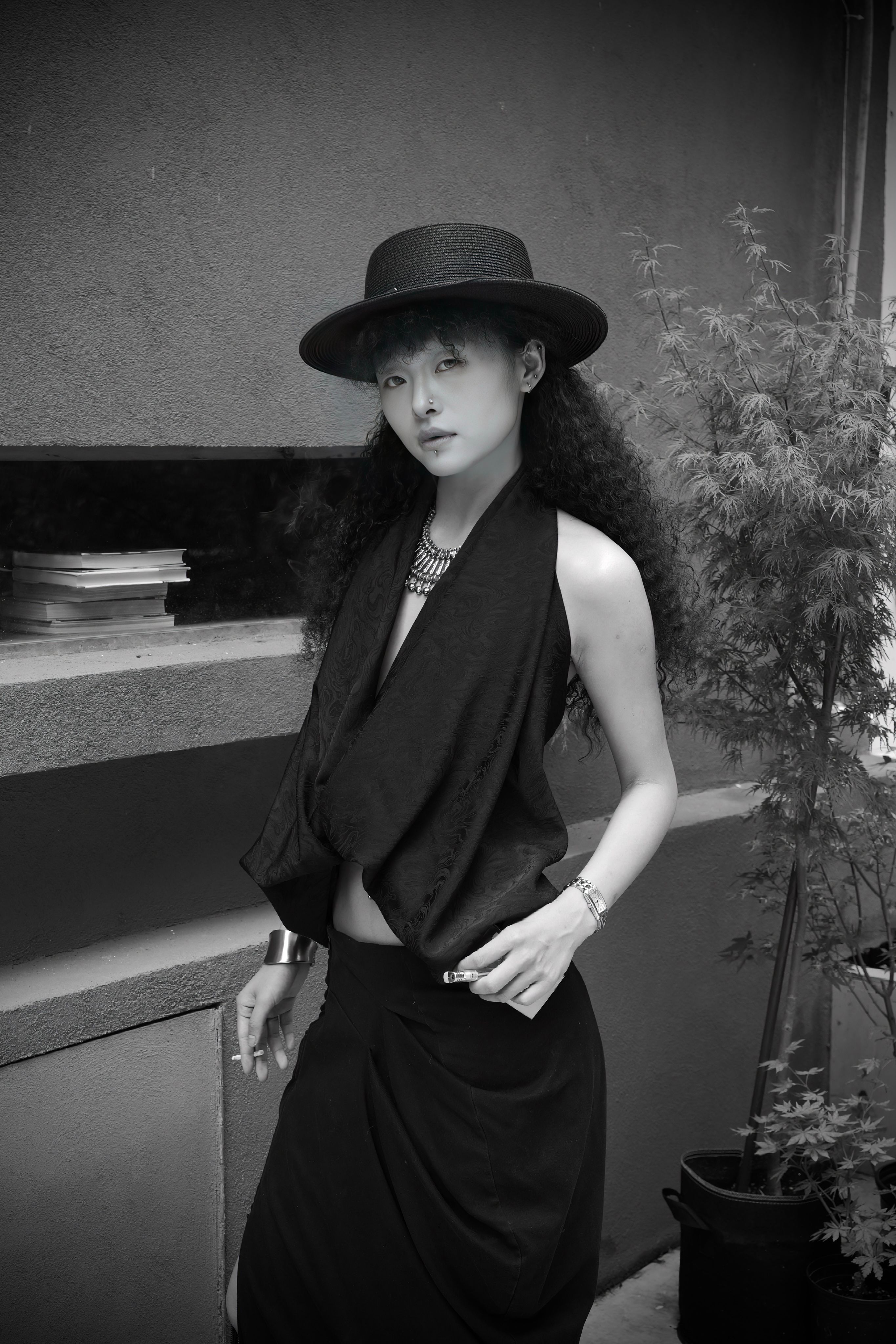 Stylish woman in black hat and attire posing elegantly outdoors.
