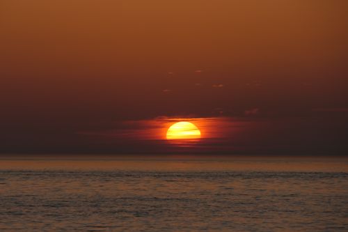 Free Stunning sunset over the North Sea with vivid orange and red hues reflecting on gentle waves. Stock Photo