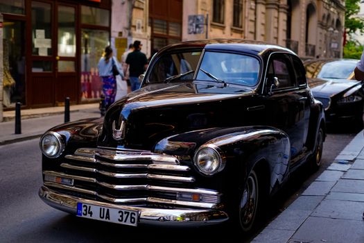 Vintage black car parked on a European street with a classic design and urban backdrop.