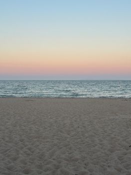 Peaceful beach scene with vibrant sunset colors reflecting on the ocean, creating a tranquil atmosphere.