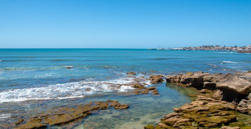 Free Capture of the rocky coastline in Cascais, Portugal, featuring clear blue waters and a bright sky. Stock Photo
