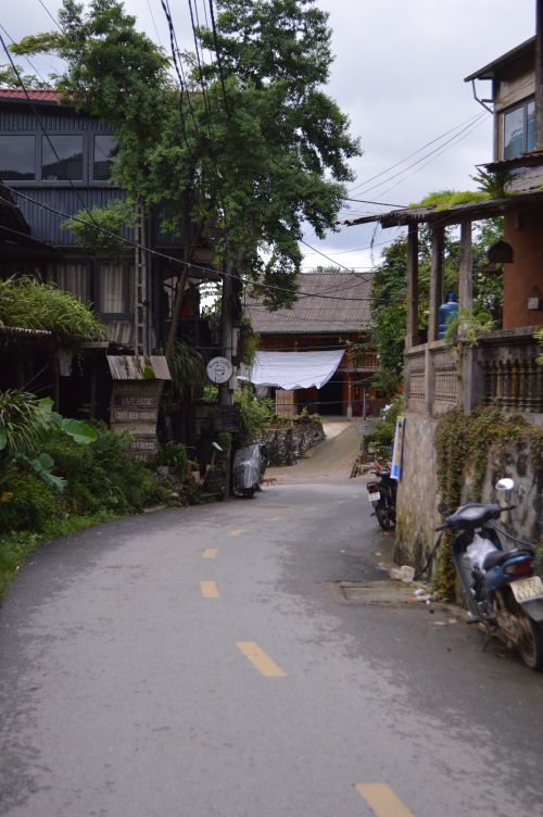 Free Quiet narrow street in a picturesque village with lush greenery and rustic buildings. Stock Photo