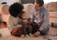 一家人在舒适的客厅里用智能手机与幼儿互动