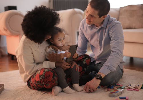 一家人在舒适的客厅里用智能手机与幼儿互动