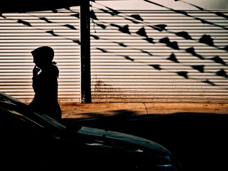 A silhouette of a person walking along a sunlit street in Istanbul, casting vivid shadows.